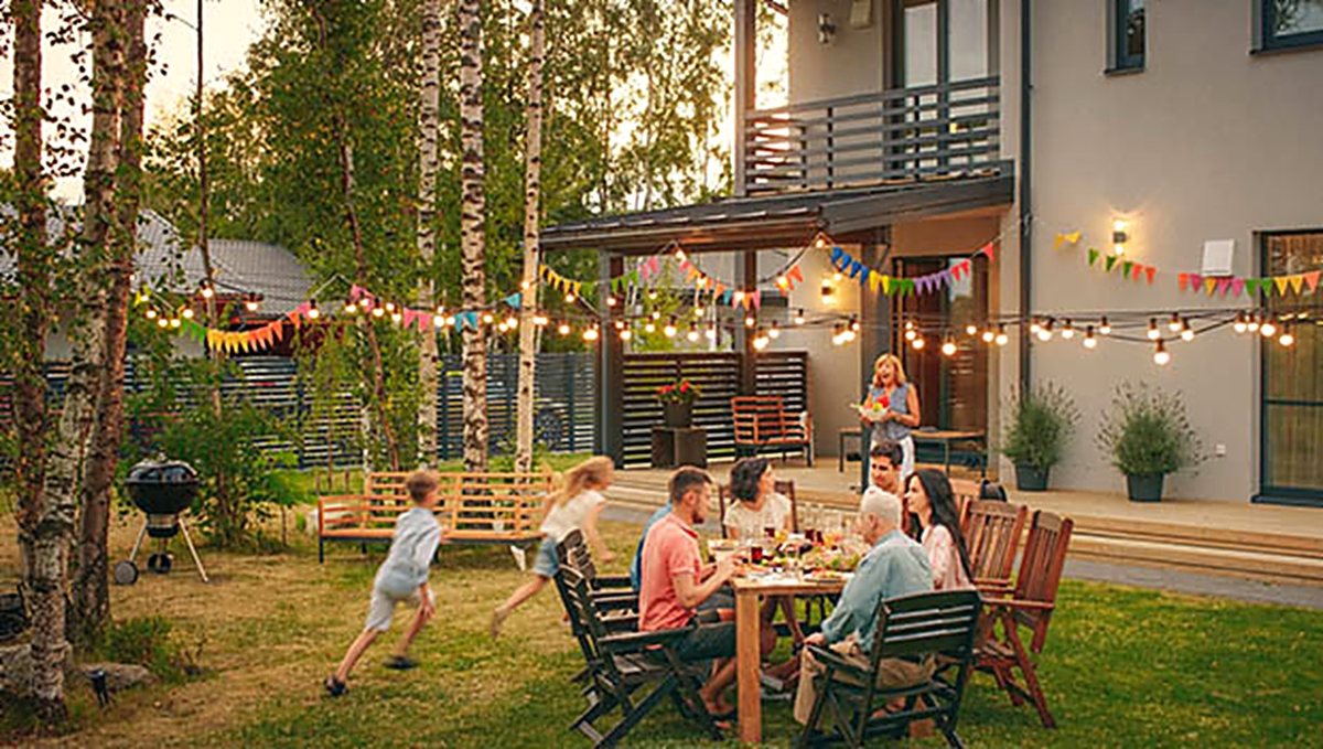 A family eating dinner together at a table in the backyard on a summer evening