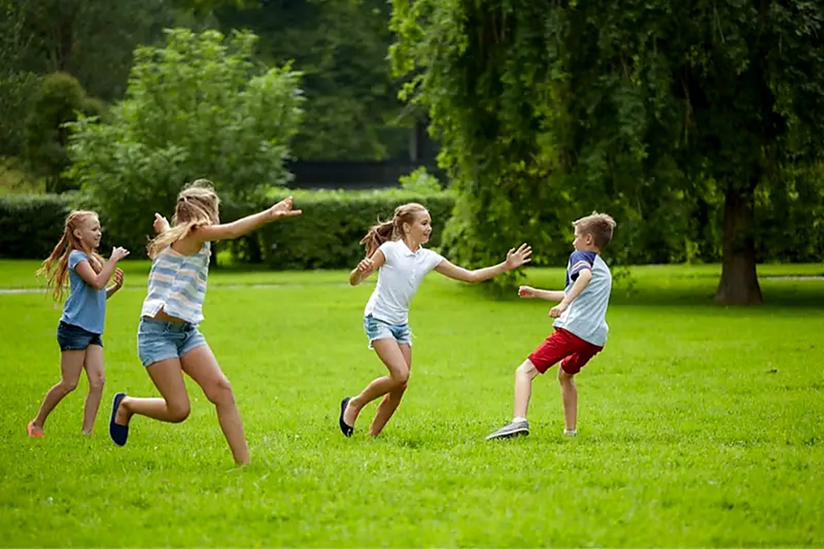 Children running and playing tag on a green lawn